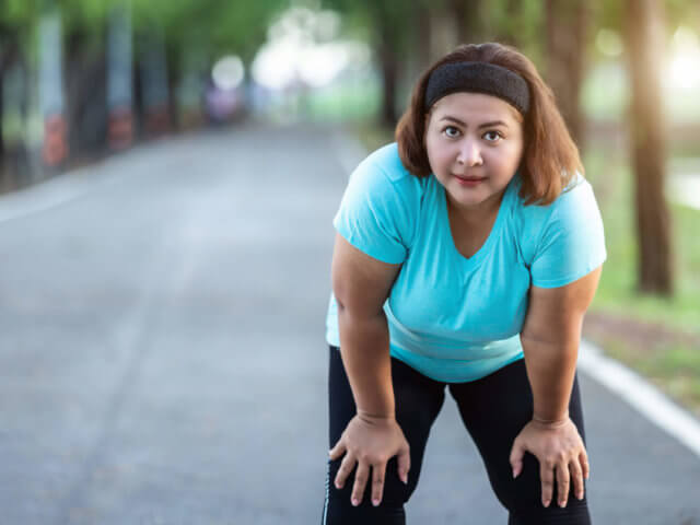 Fat woman feeling tired while running in the park