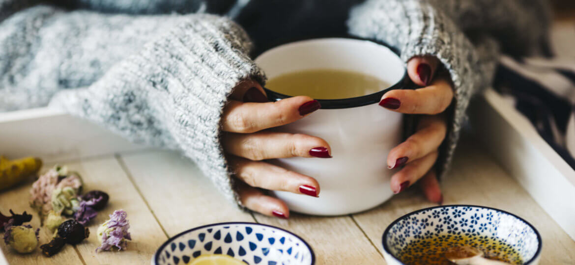 A female model is drinking herbal tea for flu, she is pouring herbal tea into a white enamel cup