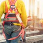 Working at height equipment. Fall arrestor device for worker with hooks for safety body harness on selective focus. Worker as a background.