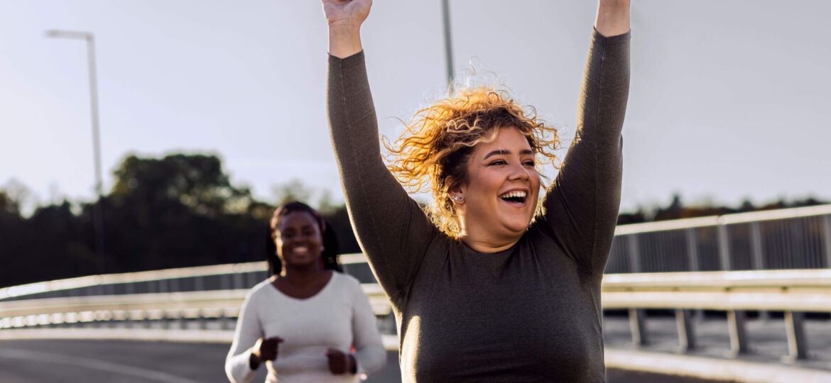 Two excited young plus size women jogging together.