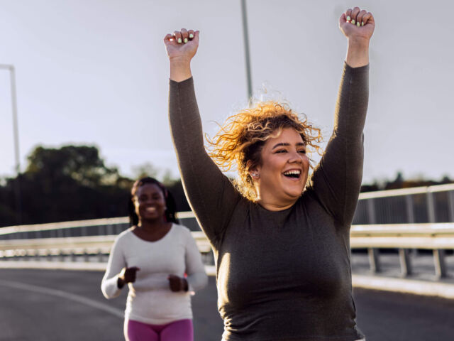 Two excited young plus size women jogging together.